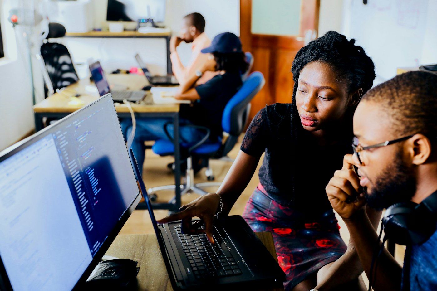 Two colleagues working through a problem together on a laptop