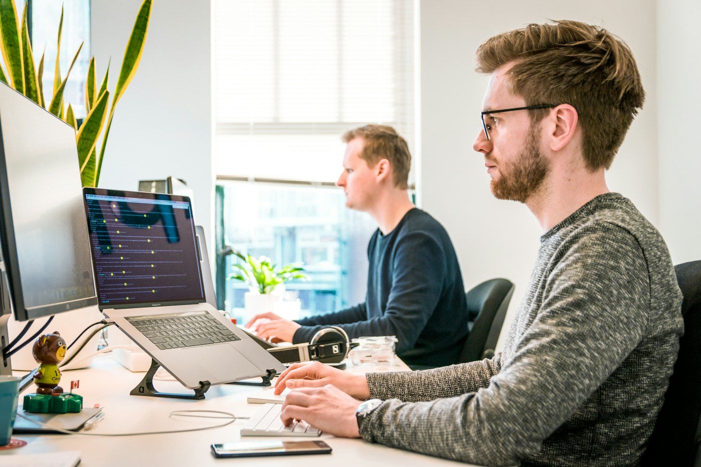 Two IT specialists working at their desks in a bright office